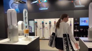 dyson rons. Bir ev aletleri mağazasının içindeki elektrikli süpürge ve diğer ekipmanlarla bir kız mağazada dolanıp Luluemon Vancouver 2023 'ün kız çantalarındaki son teknolojiye bakıyor.