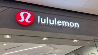 Lululemon, kasiyerdeki mağazadan spor kıyafetleri alıyor. Genç bir kızın aldığı çantaya yeni kıyafetler koyuyor. Vancouver 2023.