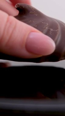 Beyaz üzerine izole edilmiş çikolata kaplı kurabiyenin üst görüntüsü. Bir kadın eli tabağa güzel bir kıvırcık marshmallow koyar. Çikolatalı tatlı. 