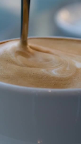非常开胃的咖啡泡沫用勺子快速搅拌它在白杯背景下任何广告屏幕保护程序的音乐拿铁咖啡加牛奶 — 图库视频影像