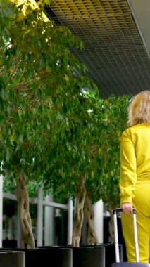 Havaalanı kadınına elinde tekerlekli bavulla gelen ya da giden sarı bir takım elbise içinde telefon konuşması yapan bir bavul. Hoşça kal iletişimi. 
