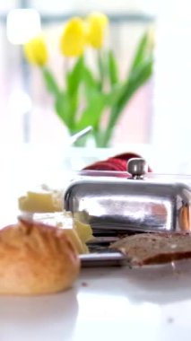 Kırık ekmek kırıntıları üzerinde gerçek kahvaltı tereyağlı şeker kasesi sütü veya cam bir pencerede kefir güneş üç sarı lale beyaz masa 