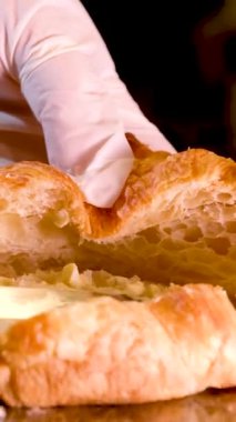 Kruvasan pişirdikten sonra karalama ruloları. Ev yapımı ya da yakın plan yemek pişirmek. Eldivenli ve tereyağlı bir bıçak fırından yeni çıkmış bir kruvasan üzerinde Fransız kahvaltısı.