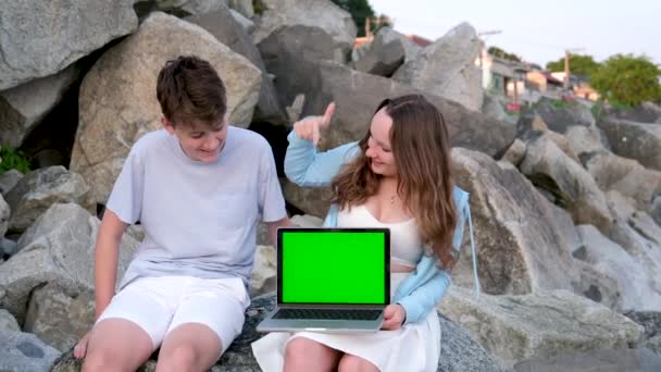 Genç Çift Taşların Üzerinde Oturuyor Yeşil Ekranlı Dizüstü Bilgisayarı Işaret — Stok video