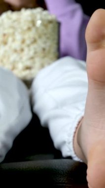 Gençler yerde oturur, netflix izler büyük ekran ekranında flaşlar siyah arka planda kırmızı mavi ellerinde patlamış mısır olan genç bir kadın. 