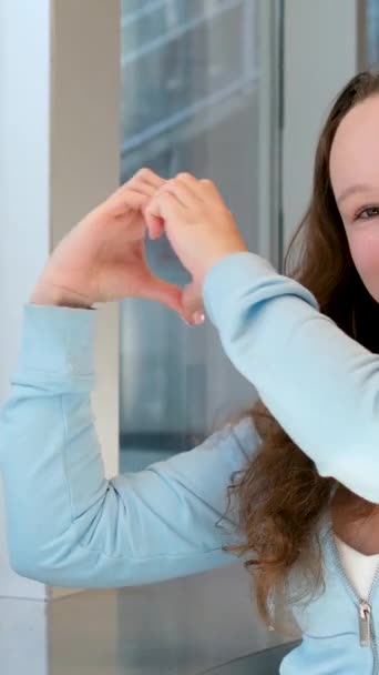 Ніжна Красива Дівчина Робить Серце Руками Посміхається Сидить Столом Біля — стокове відео