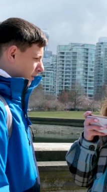 Stanley Park gençleri gezip fotoğraf çekiyorlar. Ağaçlara bakıyorlar. Baharda sohbet ediyorlar. 