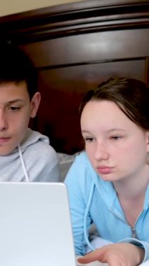 İki kız ve oğlan oturma odasındaki bir yatakta dizüstü bilgisayar kullanıyorlar. Yüksek kalite fotoğraf