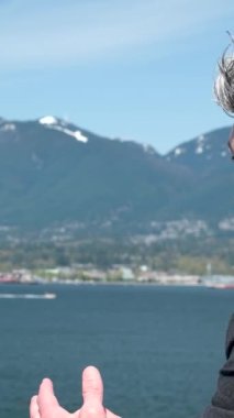 Takım elbiseli yakışıklı gri saçlı adam su kenarında durup dağlara ve Kanada 'da huzur dolu bir barış tatiline bakıyor. Vancouver Pasifik Okyanusu Kanada, gemi ofis müdürü müdürüyle yelken açıyor.