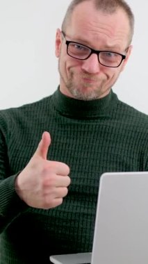 Gözlüklü ve bıyıklı yetişkin adam çok mutlu. Elinde gri bir dizüstü bilgisayarı var. 