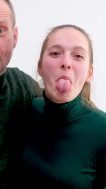 男人和女孩靠在一边 在背光下伸出舌头拍照 父亲和女儿是老师 丈夫是绿色毛衣的妻子 — 图库视频影像