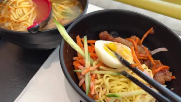 台湾風冷乾麺半熟卵台湾料理アジア料理黒皿 箸で野菜の下から春雨を茹でるキュウリニンジンをジュリエンヌの健康に切る — ストック動画