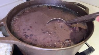 Çirkin, iştah açıcı olmayan, tencerede kaynatılmış fasulye kepçeli çamur ile toplanıp nahoş bir şekilde geri dökülerek kötü servis edilen sağlıklı yemeklerin soba pişirme fasülyesi çorbasında sıvı yapmasını izlemek.