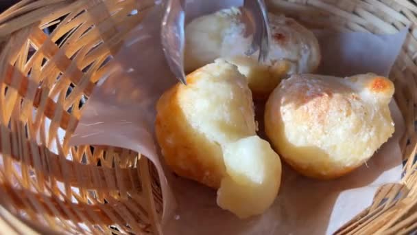 木製のテーブルの上に紙袋に典型的なブラジルチーズパン 白ナプキンの皮を編んだバスケットからチーズパン3つ一緒においしい料理パン — ストック動画