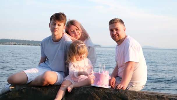 家族みんなフレームママはリボンで遊んでいる息子のお父さんの弟と妹の肩の上にある3年ケーキピンク誕生日ビーチの美しさ家族の幸せ赤ちゃん — ストック動画