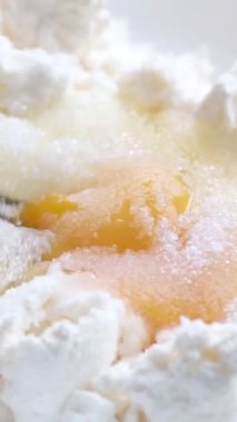 Beyaz tabakta, peynirli yumurta şekeri kadın elleri yumurtaları çatal delici sarısı ile süzme peynirle karıştırıp peynirli kekle yoğurur. 