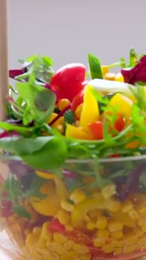 wooden spoons stir salad in glass plate corn tomatoes cucumbers bulgarian yellow peppers arugula leaves vegetarian food lunch slimming diet close-up female hands