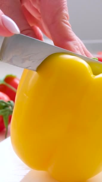 用小刀在白瓷板上切成两半的黄椒女手很多蔬菜樱桃西红柿黄瓜玻璃器皿 — 图库视频影像