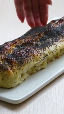 Elmalı turta haşhaş tohumları serpiştirilmiş büyük bıçaklı kadın eli yakından kesilmiş lezzetli kokulu tatlı kırmızı elma uzayı metni. 