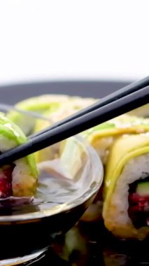 Menü yeşili Japon dürümleri avokado, omlet, susam ve salatalık tabakta yakın plan. Yatay bir şekilde, siyah bir restoranda nefis Japon yemekleri servis ederken.