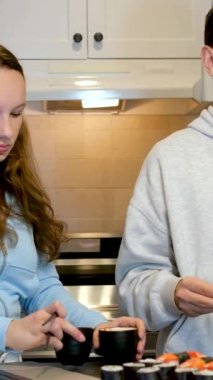 Dizüstü bilgisayarlarda film seyreden genç kız eğleniyor. Mutfakta suşi yiyor. Fast food dağıtıyor. 