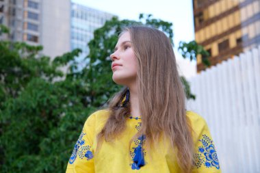 Sarı-mavi ceketli genç güzel kız güzel Ukraynalı görünümünü Avrupa görünümlü açık hava sarışını evde uzun saçlı, arka plandaki ağaçlar kadınsı kız.