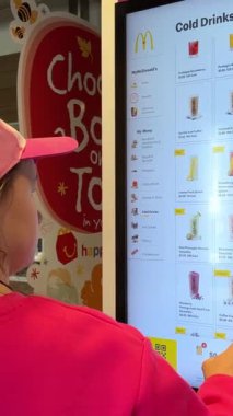 McDonales 'deki genç kız smoothies pembe elbise sipariş eder. Klasik Amerikan gençlik şapkası BC, Kanada, Vancouver, 06.30.2023