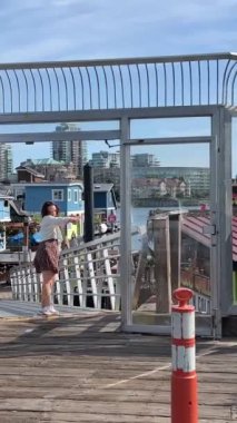 Köprüde duran bir kız manzaranın içine girmeye çalışıyor. İyi hava balıkçıları rıhtımının girişi, Vancouver Adası, BC girişi, Vancouver, Kanada, 07.07.2023.