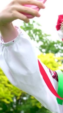 Geleneksel halk görüntüsünde Ukraynalı bir kadın telefona bakarak selfie çekiyor. Aynada güzel bir çelenk, bir sürü beyaz çiçekle genç bir kızın güzelliği Ukrayna 'da savaş neşesi yok.