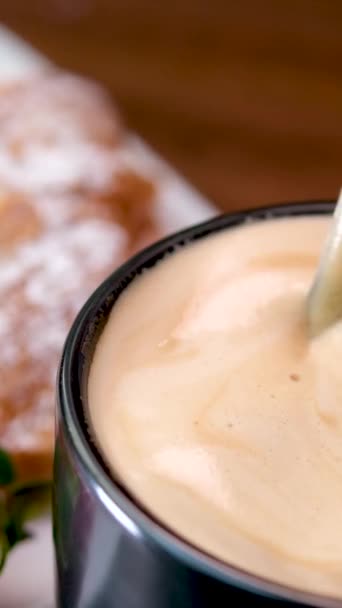 朝食に焼きたてのフランスクロワッサンを食べるラテカプチーノミルクとスプーン厚い泡のコーヒーと攪拌 — ストック動画
