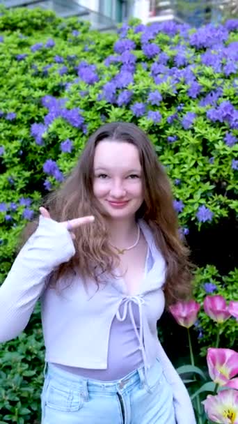 소녀는 공원에 주름진 광고를 기뻐하면서 손가락을 치켜세우고 옆으로 치켜세우면 놀라서 — 비디오