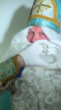 Noel Baba turkuaz takım elbisesinin kurucusu Aziz Nicholas 'ın farklı pozitif duyguları vardı. Geleneksel bir dini şapkayla, tıpkı bir papazın cübbesi ve kemeri olması gibi.