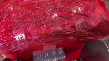 bagaj paketleme noktası kırmızı plastik film havaalanı Vancouver Kanada 'da mavi yeşil bavulu çevrelemektedir.
