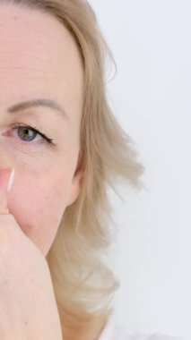 Sümüklü burun alerjisi olan bir kadın elini beyaz arka plan ilaçlarına sürerek burnunu siliyor.