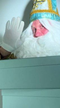 Noel Baba Donduran Moroz Ivanovich kış ayı Moroz elini sallayarak kutuları tutuyor ve parmağıyla onları işaret ediyor.