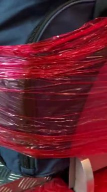 bagaj paketleme noktası kırmızı plastik film havaalanı Vancouver Kanada 'da mavi yeşil bavulu çevrelemektedir.