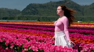 Pembe elbiseli ve hasır şapkalı genç kadın lale tarlasında duruyor. Bahar geldi. Yüksek kalite fotoğraf