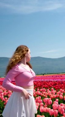 Pembe elbiseli ve hasır şapkalı genç kadın lale tarlasında duruyor. Bahar geldi. Yüksek kalite fotoğraf