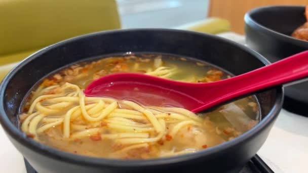 赤いオリエンタルスプーンアジア料理のブラックプレートにオリエンタル麺スープ ランチディナーファーストコース — ストック動画