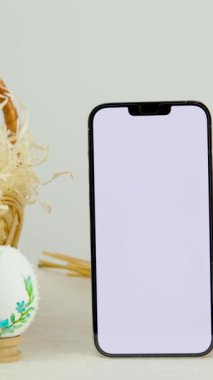 Easter holiday phone show thumb up empty space for advertising In basket eggs with embroidered pattern ribbon embroidery on eggshells wheat spikelets on table place for dough close-up basket