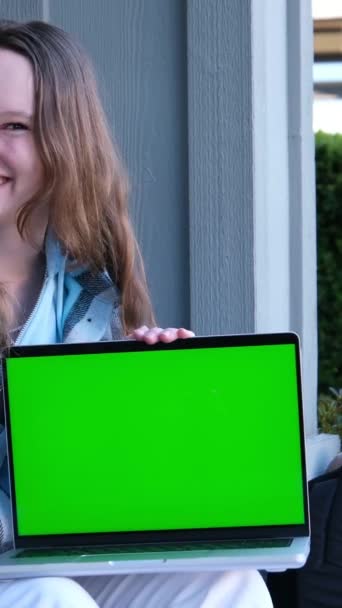 喜びサプライズ幸せ少女は スクリーン広告インターネット学習エンターテイメントスポーツで指を指すストリートティーンエイジャーに座っている緑色のスクリーンクロマキーとラップトップを保持しています — ストック動画
