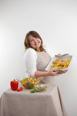 Smiling young woman serving fresh salad on plate. Happy smiling cute woman cooking fresh healthy vegan salad at home with many vegetables in kitchen and trying new recipe High quality photo