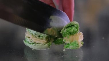 Bıçakla yeşil badem kurabiyesi kes. kireç fıstıklı zeytin yeşil makarna cam bir masada çelik bıçakla kesilmiş.
