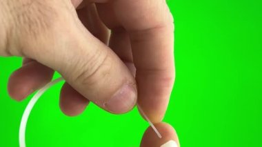 On a green background, a chromakey man fastens a nylon tie with his own hands. He pulls the long end through the hole and secures it nylon tie