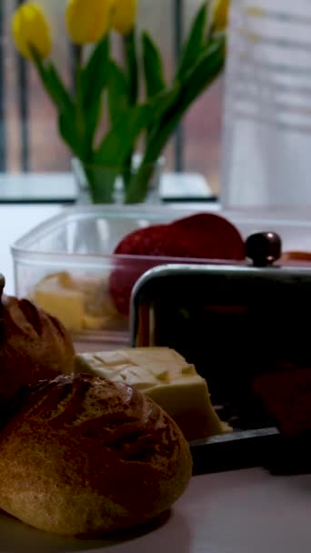 テーブルの上の本当の朝食壊れたパンパン粉バター砂糖ボウルミルクやケフィアでガラス窓の太陽3つの黄色チューリップホワイトテーブル — ストック動画