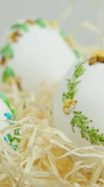 Easter three beautiful embroidered eggs with eggshell ribbons in nest with wrapping paper white background space for text congratulations meeting with family decoration home decoration gift delivery