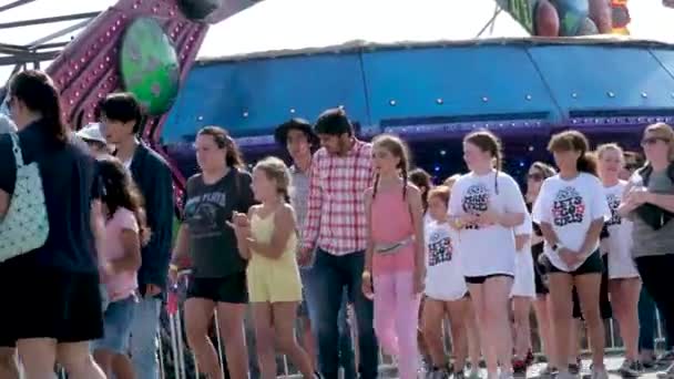 游乐园的成人和儿童在秋千的背景下漫步 人们花时间和家人一起买票 加拿大温哥华2023年 大批头戴牛仔帽度假的加拿大民众 — 图库视频影像