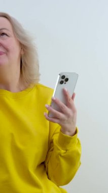Utanç verici turuncu kazaklı kadın elinde telefonla dikiliyor utangaç gözleri kapanıyor yüzü kızarıyor dişleri kızarıyor başları birbirine değiyor 