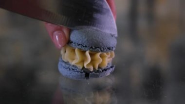 Koyu cam arka planda büyük bir bıçakla kesilmiş mavi makarna gevşemiş gevşek, lezzetli ve süpürülmüş hamur işi. Dişi el, dolgu malzemelerini keserek açıyor.