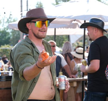 Eğlence parkındaki yetişkinler ve çocuklar salıncakta sallanıyorlar. İnsanlar bilet alırlar aileleriyle vakit geçirirler. Kanada Vancouver 2023 şapkalı Kanadalı büyük bir kalabalık tatilde.